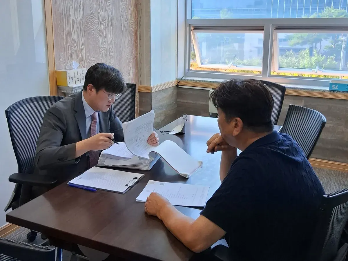 변호사가 의뢰인과 마주 앉아 서류를 설명하는 모습