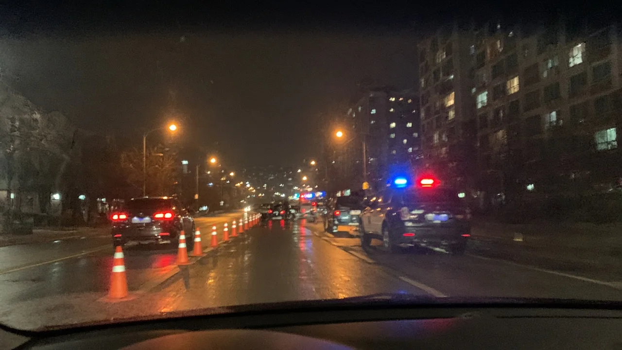 밤에 차 안에서 본 음주 단속 현장. 주황색 라바콘과 경광등을 켠 경찰차가 서 있다.